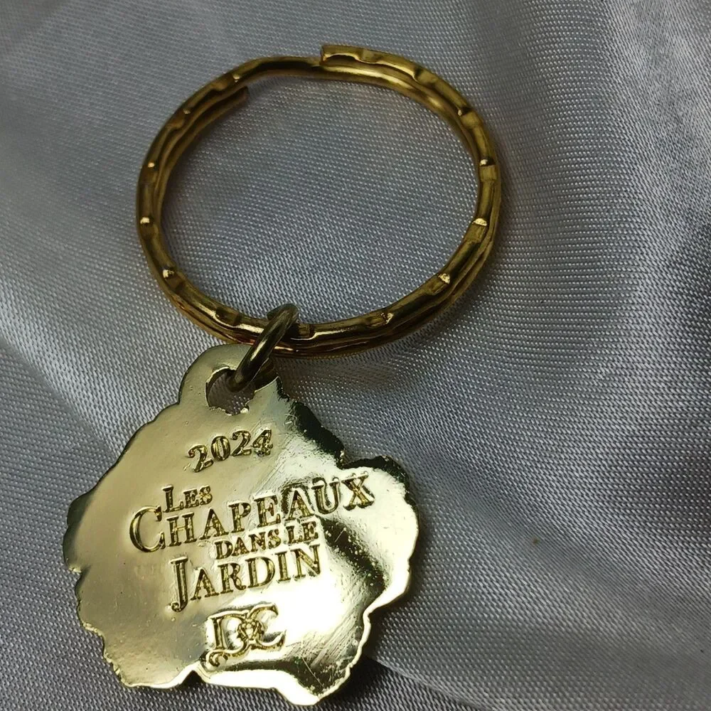 LES CHAPEAUX DANS LE JARDIN (HATS IN THE GARDEN) 2024 PURPLE FLOWER KEYCHAIN